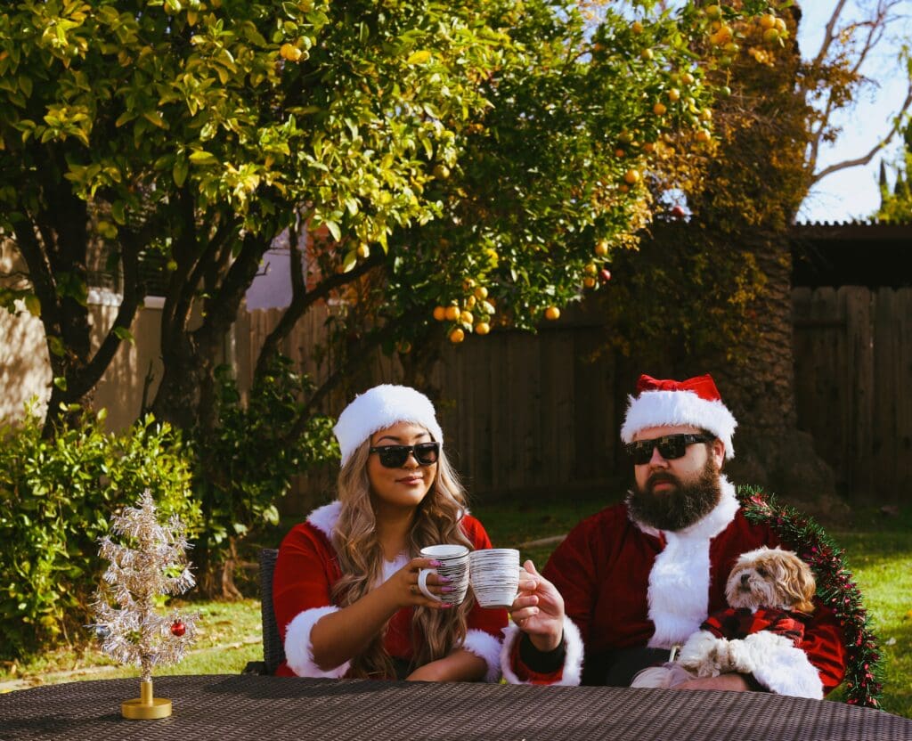 Family in Santa outfits having coffee with their dog in the yard